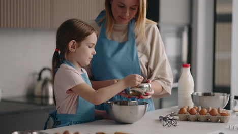 Kleines-Mädchen-Hilft-Ihrer-Mutter-In-Der-Küche.-Mutter-Und-Tochter-Kochen-Zusammen-Und-Fügen-Zucker-Hinzu